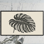 Monstera leaf art on a black TV on a white marble wall