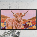 Highland cow in fall leaves art on a black TV on a white marble wall