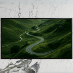 Winding road landscape art on a black TV on a white marble wall