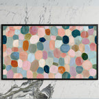 Pastel pebble mosaic art on a black TV on a white marble wall