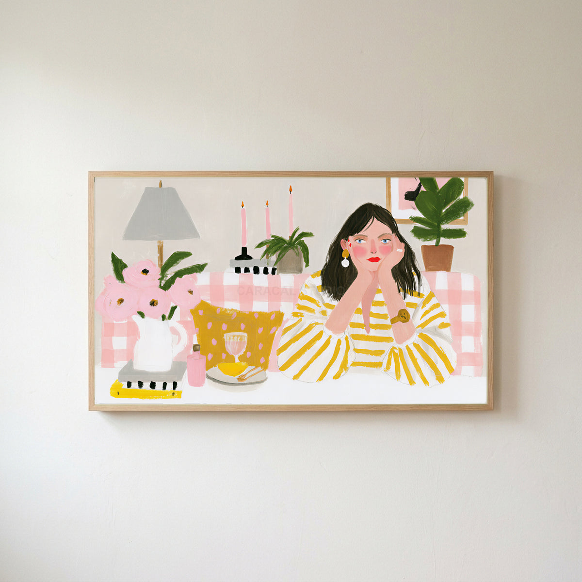Woman at a pink table Frame TV art in an oak frame on a warm white wall
