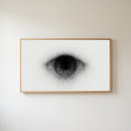Black and white eye Frame TV art in an oak frame on a warm white wall