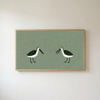 Two shorebirds Frame TV art in an oak frame on a warm white wall