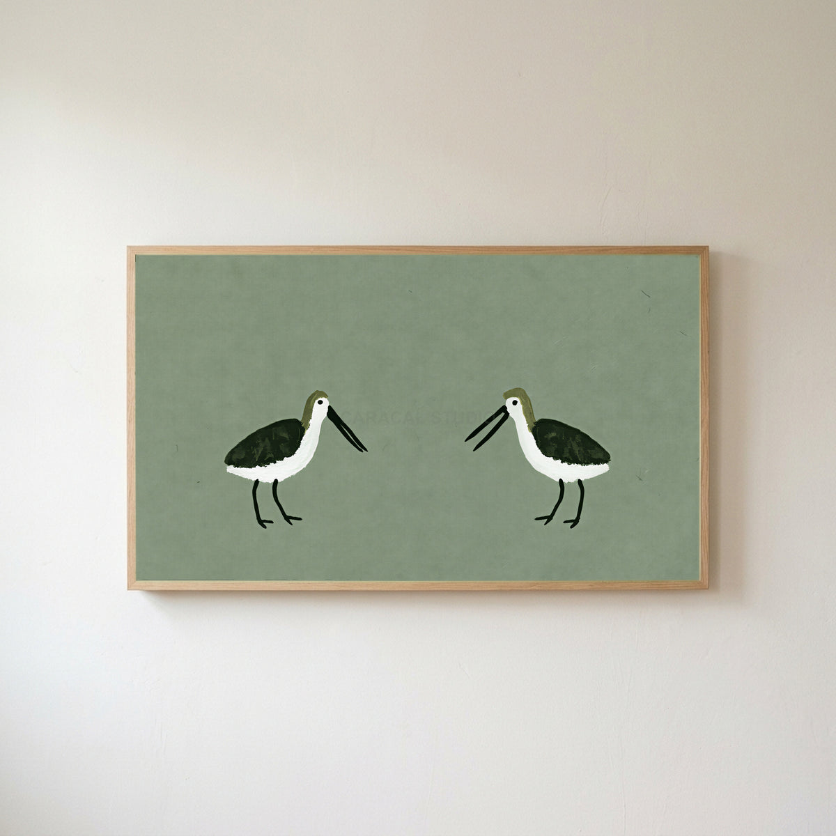 Two shorebirds Frame TV art in an oak frame on a warm white wall