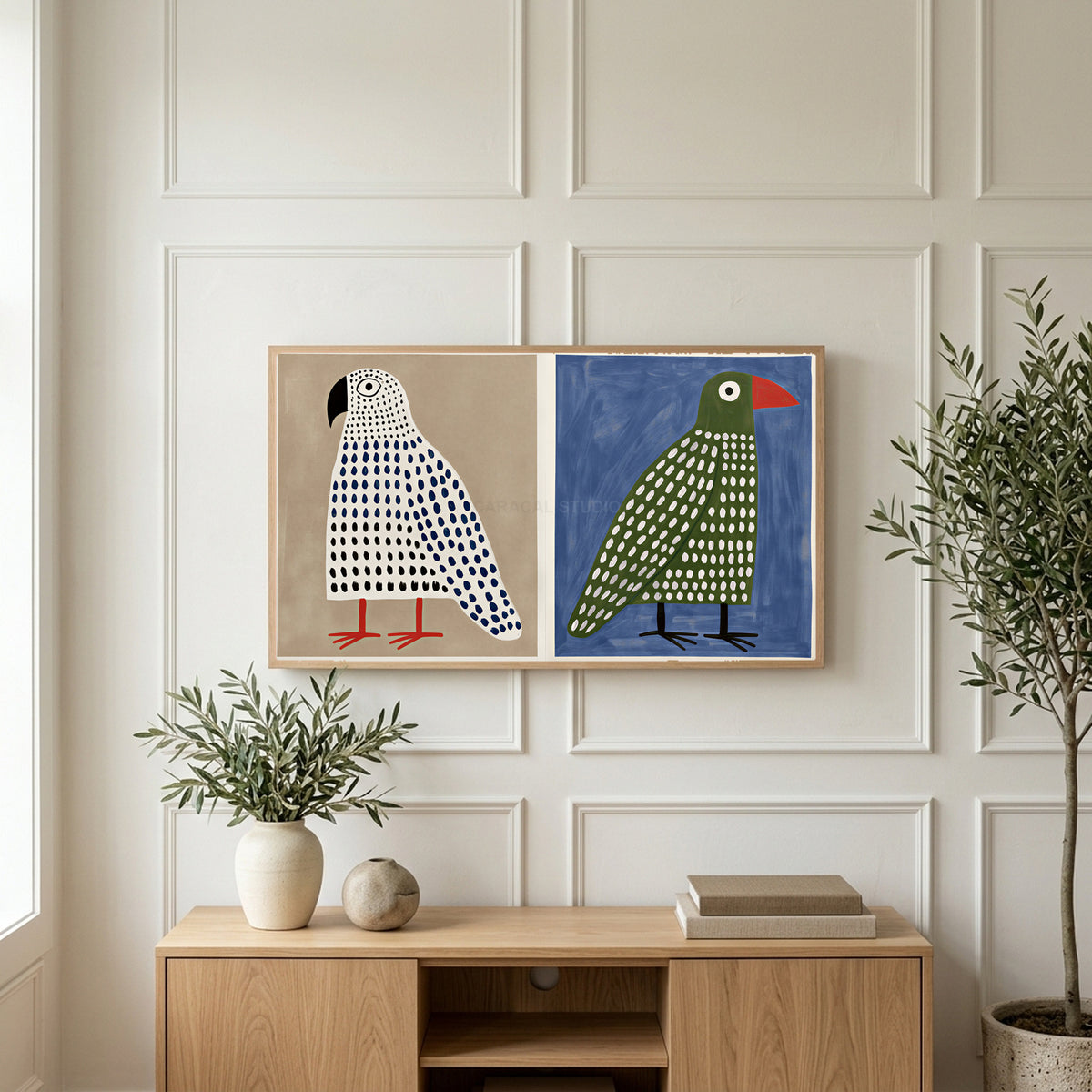 Polka dot birds art on a TV above a light oak sideboard with olive branches in a bright living room