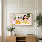 Woman at a pink table art on a TV above a light oak sideboard with olive branches in a bright living room