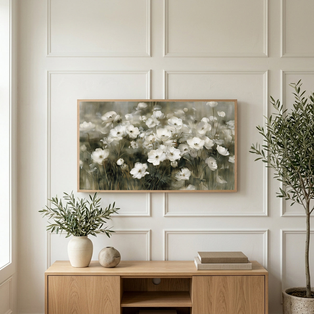 White anemone field art on a TV above a light oak sideboard with olive branches in a bright living room