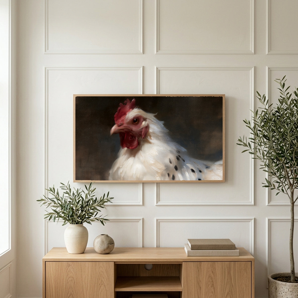 White hen portrait art on a TV above a light oak sideboard with olive branches in a bright living room