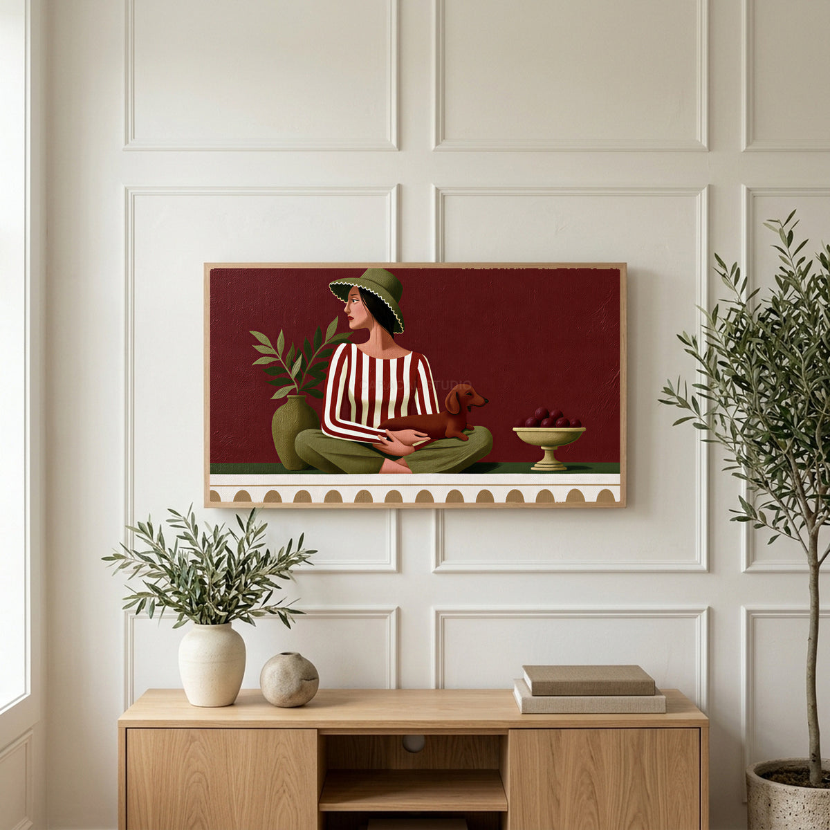 Woman with a dachshund art on a TV above a light oak sideboard with olive branches in a bright living room