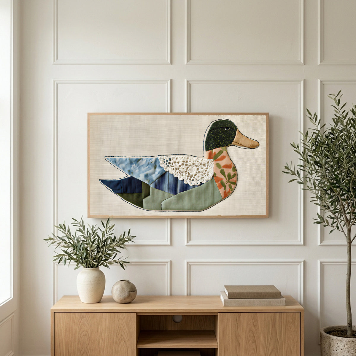 Patchwork duck art on a TV above a light oak sideboard with olive branches in a bright living room