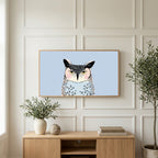 Grumpy owl art on a TV above a light oak sideboard with olive branches in a bright living room