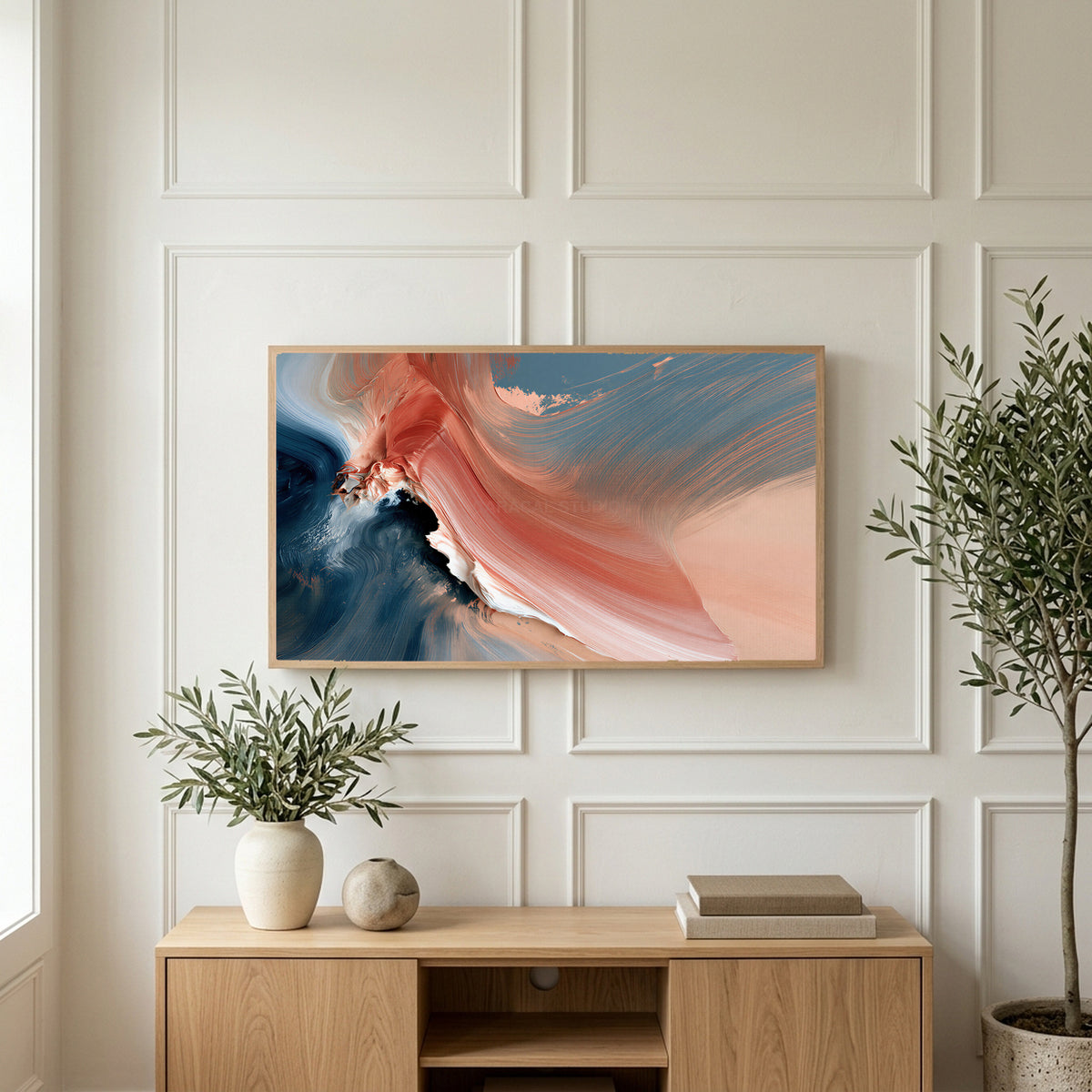Coral and navy abstract art on a TV above a light oak sideboard with olive branches in a bright living room