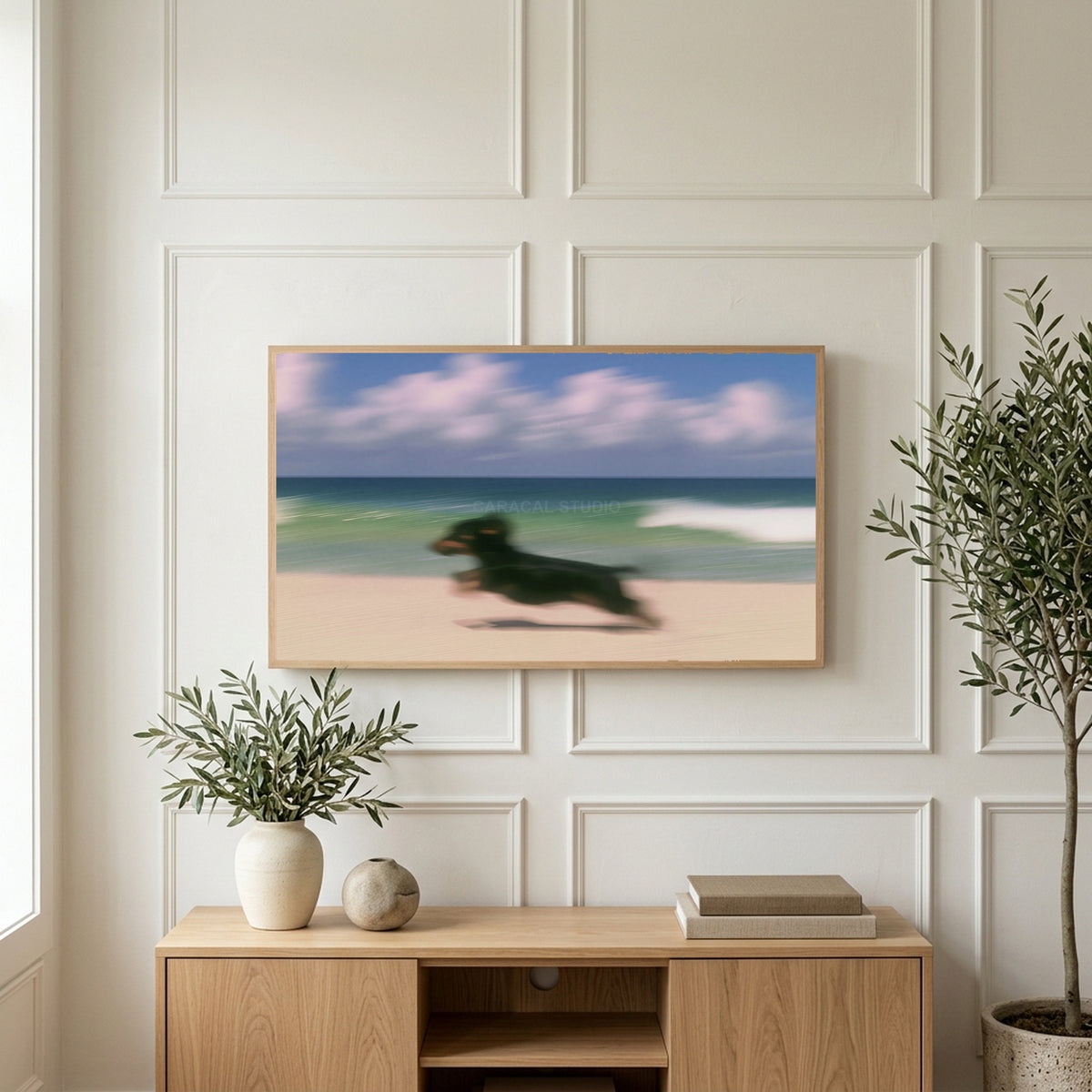 Running beach dachshund art on a TV above a light oak sideboard with olive branches in a bright living room