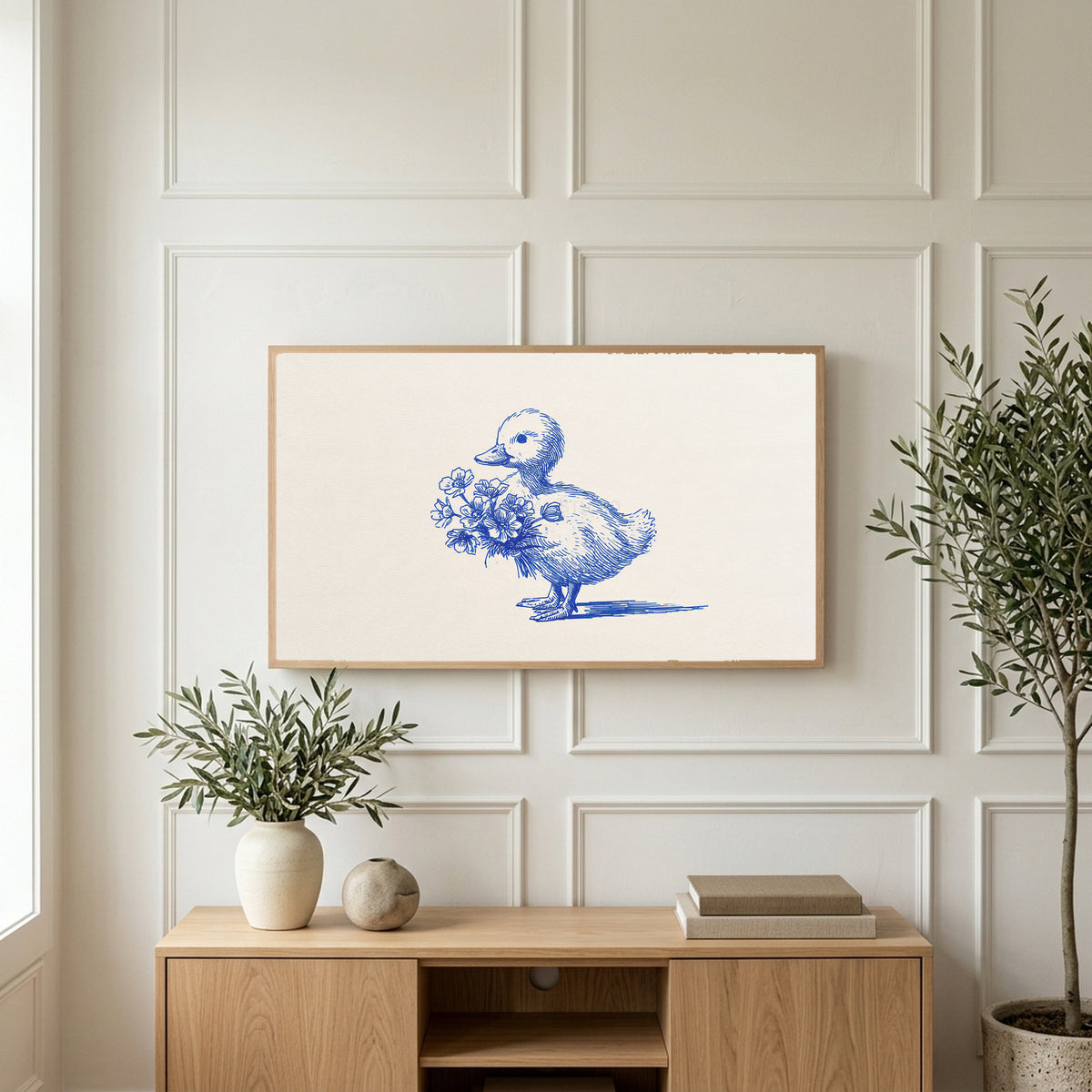 Duckling art on a TV above a light oak sideboard with olive branches in a bright living room