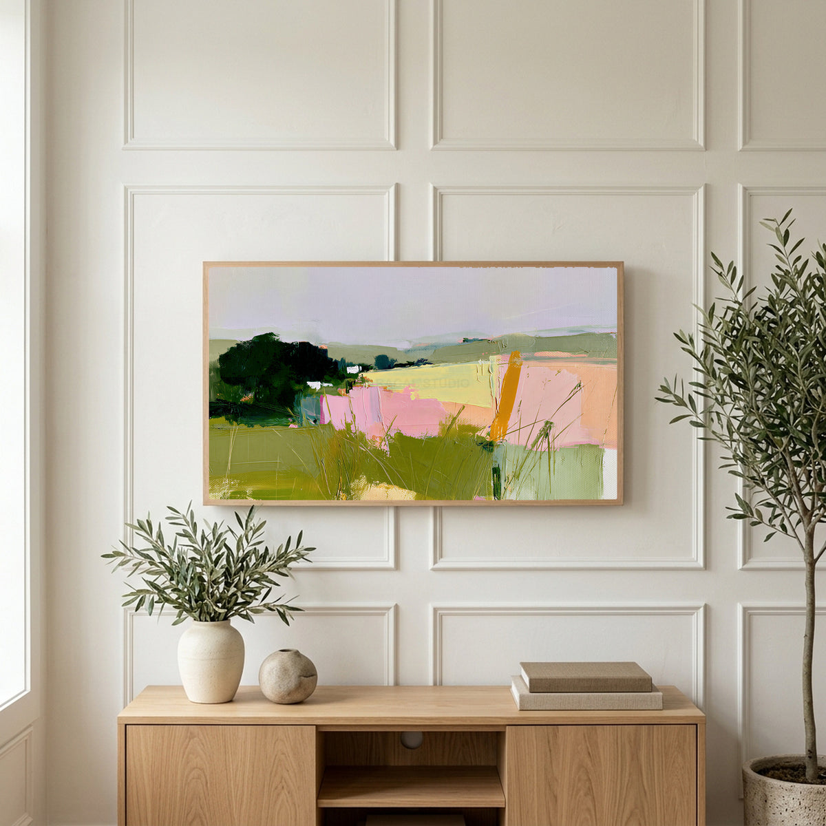 Abstract countryside art on a TV above a light oak sideboard with olive branches in a bright living room