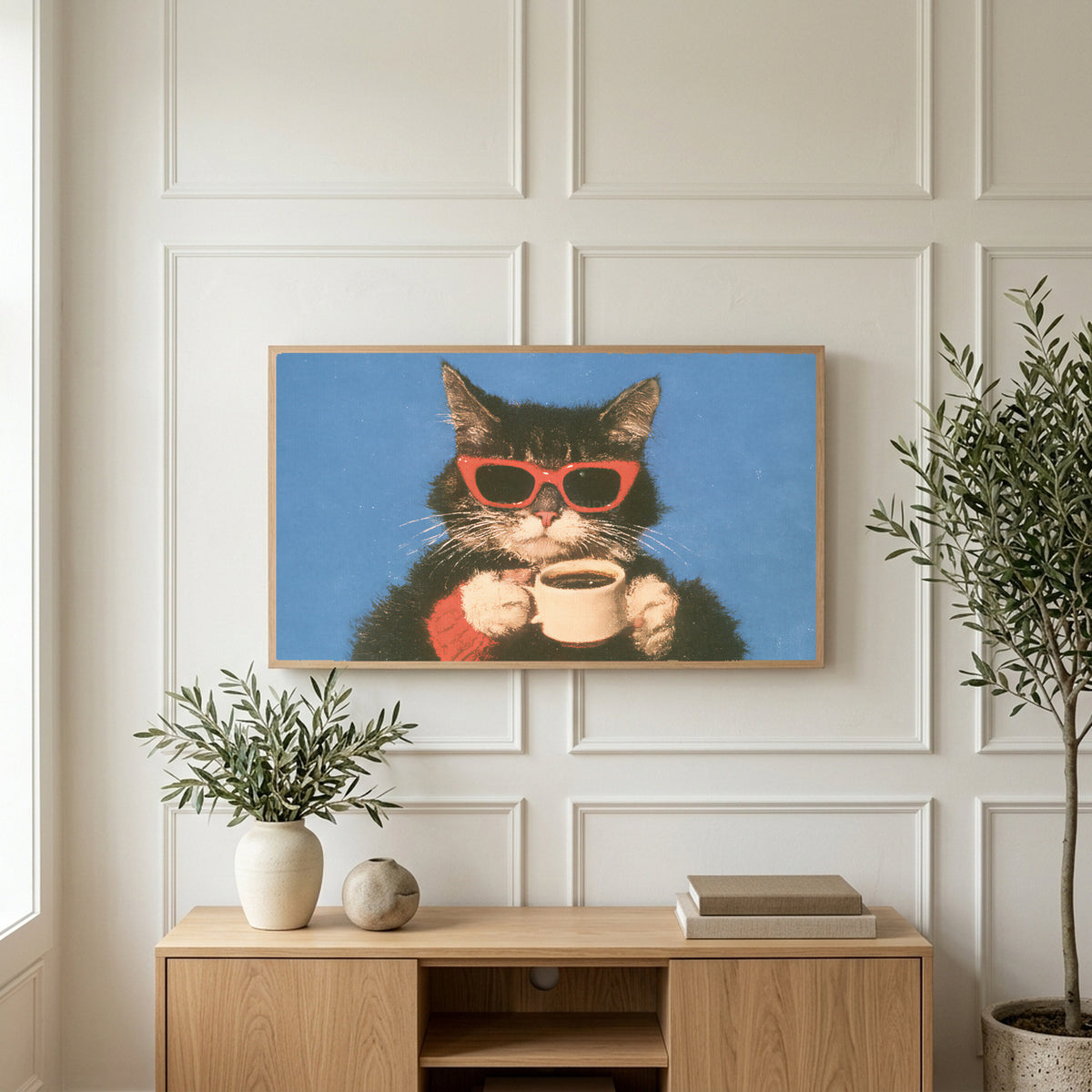 Coffee cat in sunglasses art on a TV above a light oak sideboard with olive branches in a bright living room