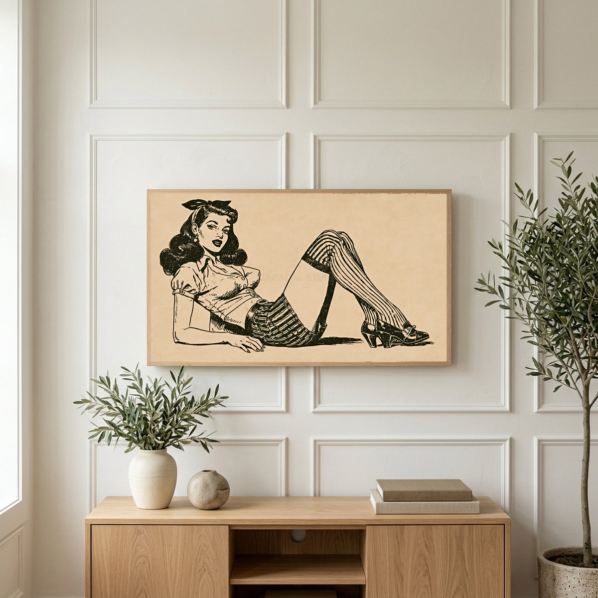 Vintage pin-up drawing art on a TV above a light oak sideboard with olive branches in a bright living room