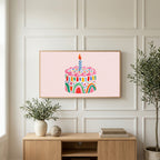 Rainbow birthday cake art on a TV above a light oak sideboard with olive branches in a bright living room