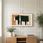Minimalist black cow art on a TV above a light oak sideboard with olive branches in a bright living room