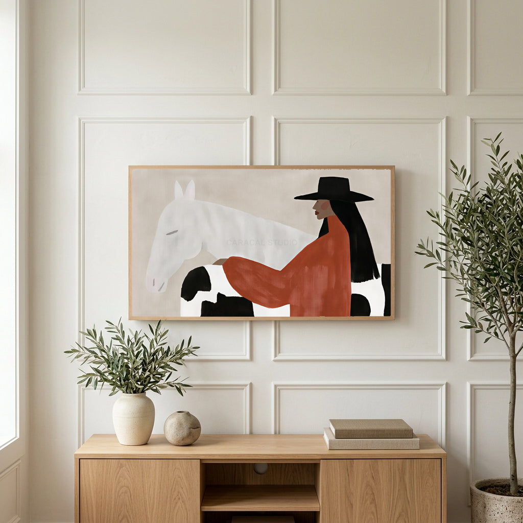 Cowgirl and her horse art on a TV above a light oak sideboard with olive branches in a bright living room