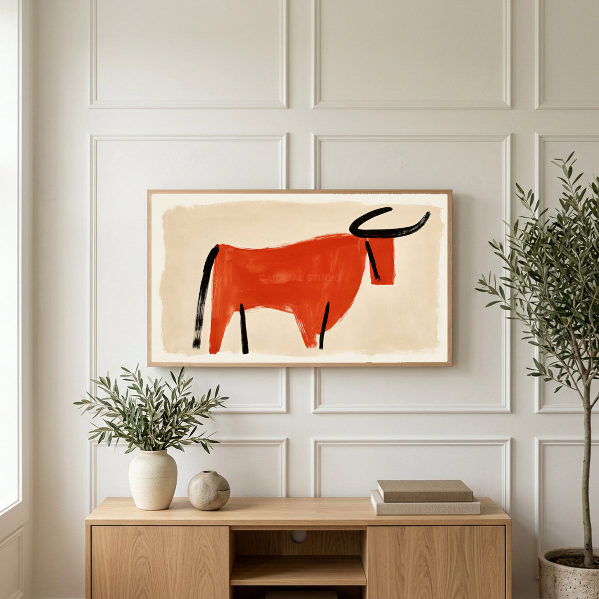 Minimalist bull art on a TV above a light oak sideboard with olive branches in a bright living room