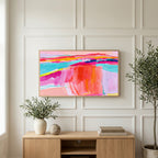 Pink abstract horizon art on a TV above a light oak sideboard with olive branches in a bright living room