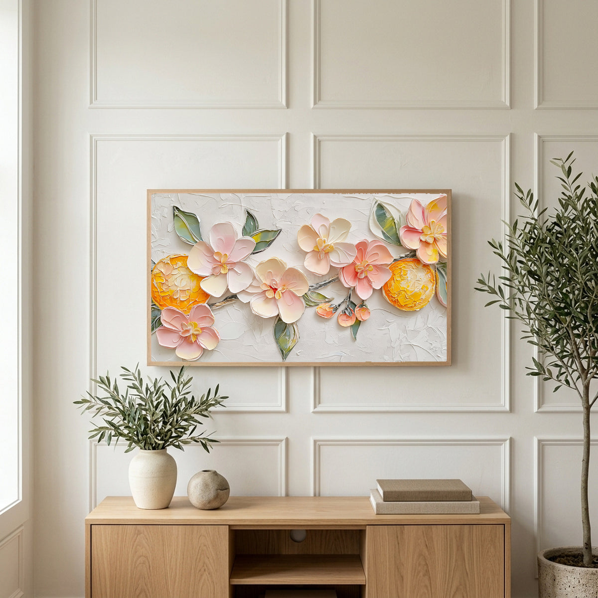 Blossom and orange art on a TV above a light oak sideboard with olive branches in a bright living room