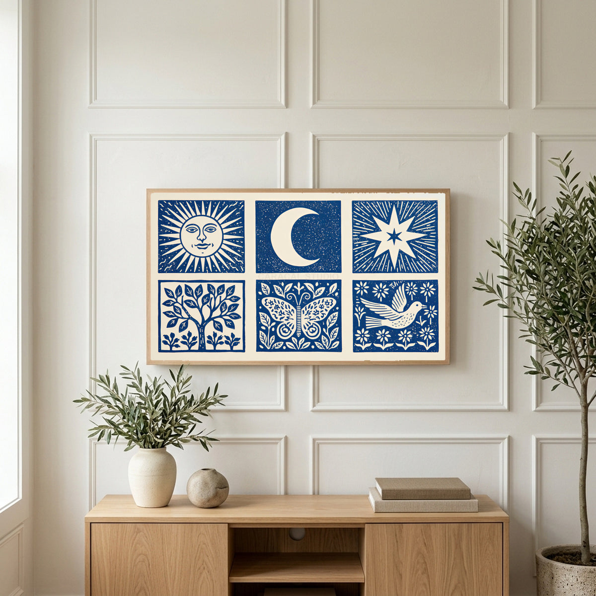 Celestial folk art on a TV above a light oak sideboard with olive branches in a bright living room