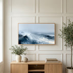 Ocean waves art on a TV above a light oak sideboard with olive branches in a bright living room