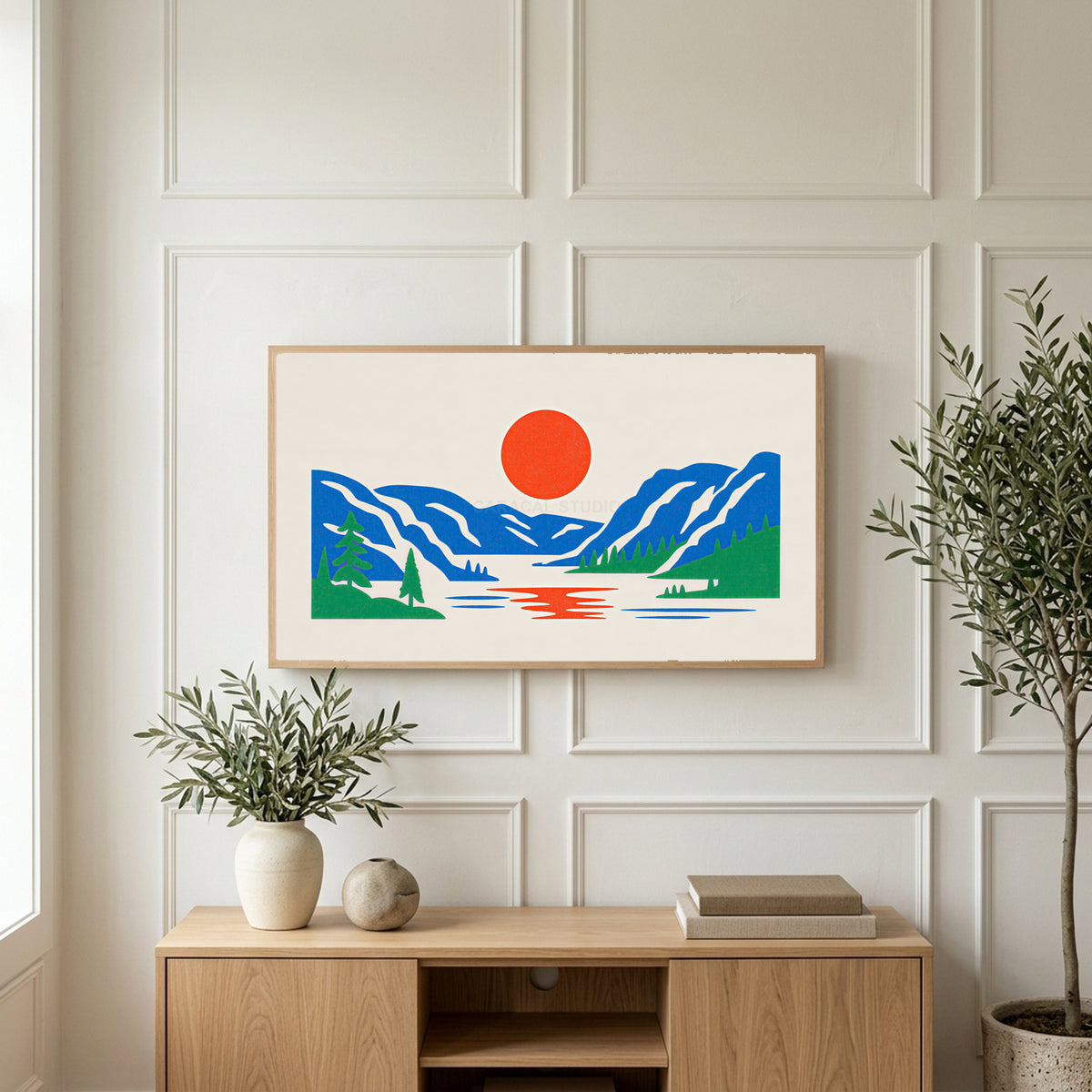 Mountain lake sun art on a TV above a light oak sideboard with olive branches in a bright living room