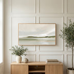 Misty sage shoreline art on a TV above a light oak sideboard with olive branches in a bright living room