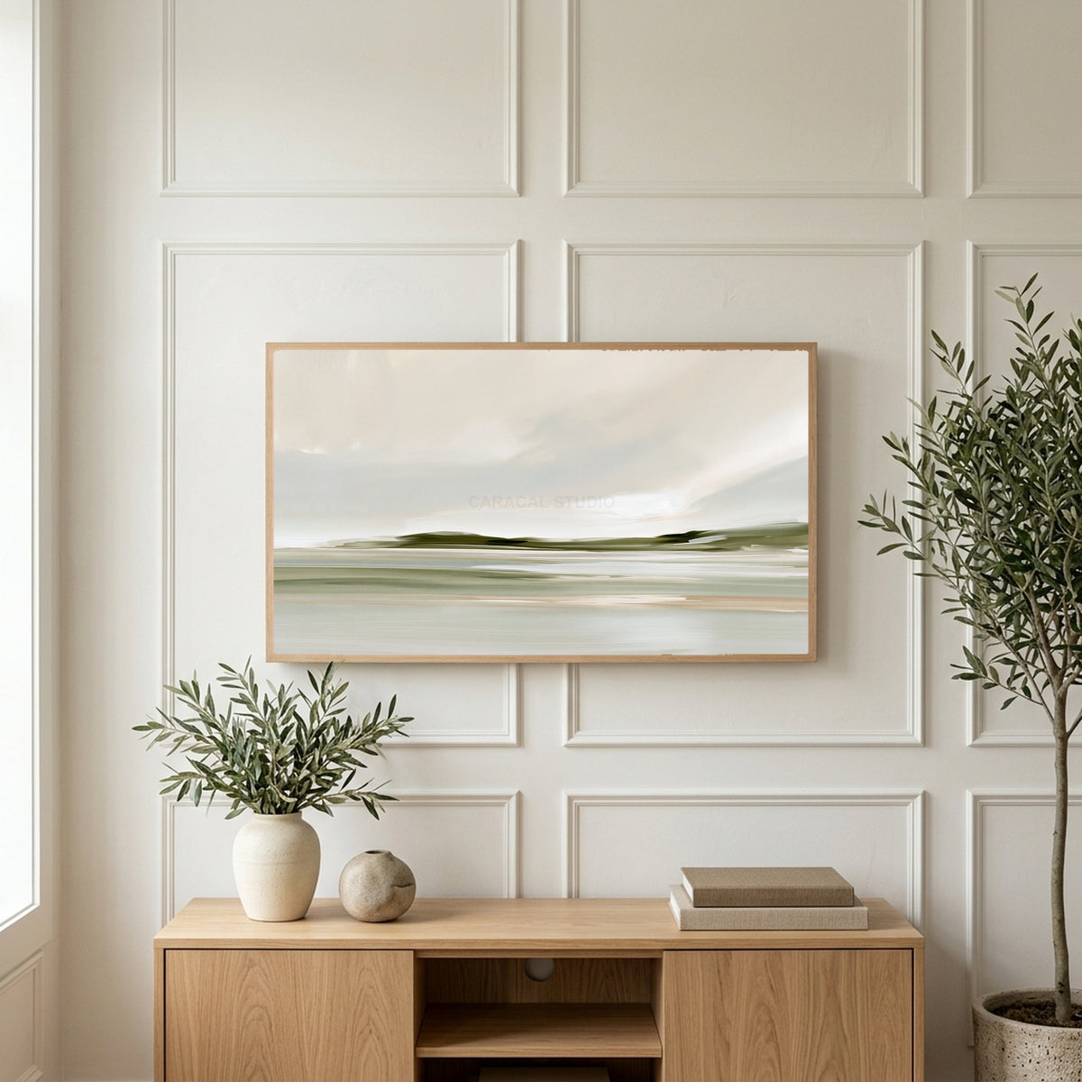 Misty sage shoreline art on a TV above a light oak sideboard with olive branches in a bright living room