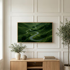 Winding road landscape art on a TV above a light oak sideboard with olive branches in a bright living room