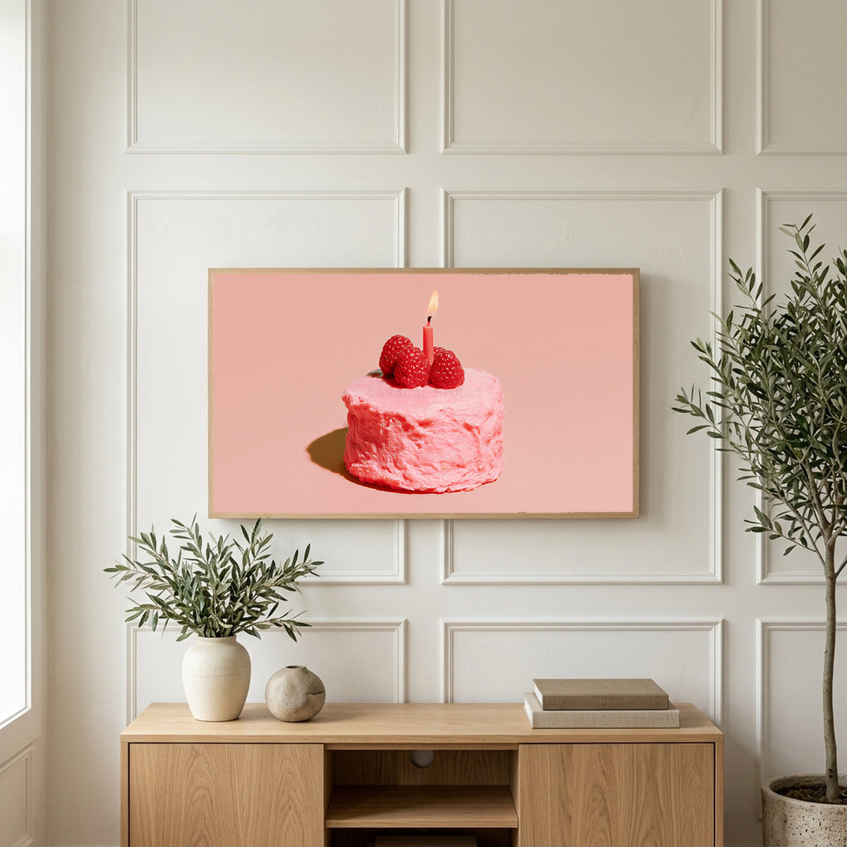 Birthday cake art on a TV above a light oak sideboard with olive branches in a bright living room
