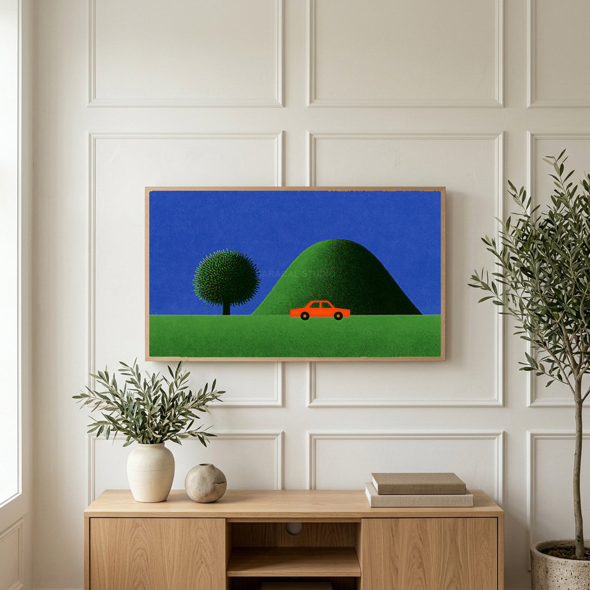 Red car by a green hill art on a TV above a light oak sideboard with olive branches in a bright living room