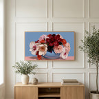 Peony and orchid bouquet art on a TV above a light oak sideboard with olive branches in a bright living room
