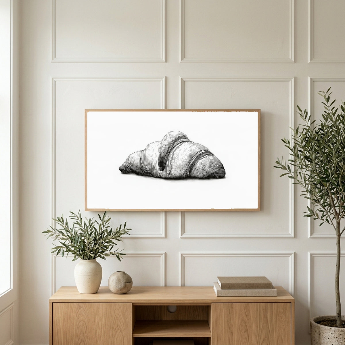 Croissant etching art on a TV above a light oak sideboard with olive branches in a bright living room