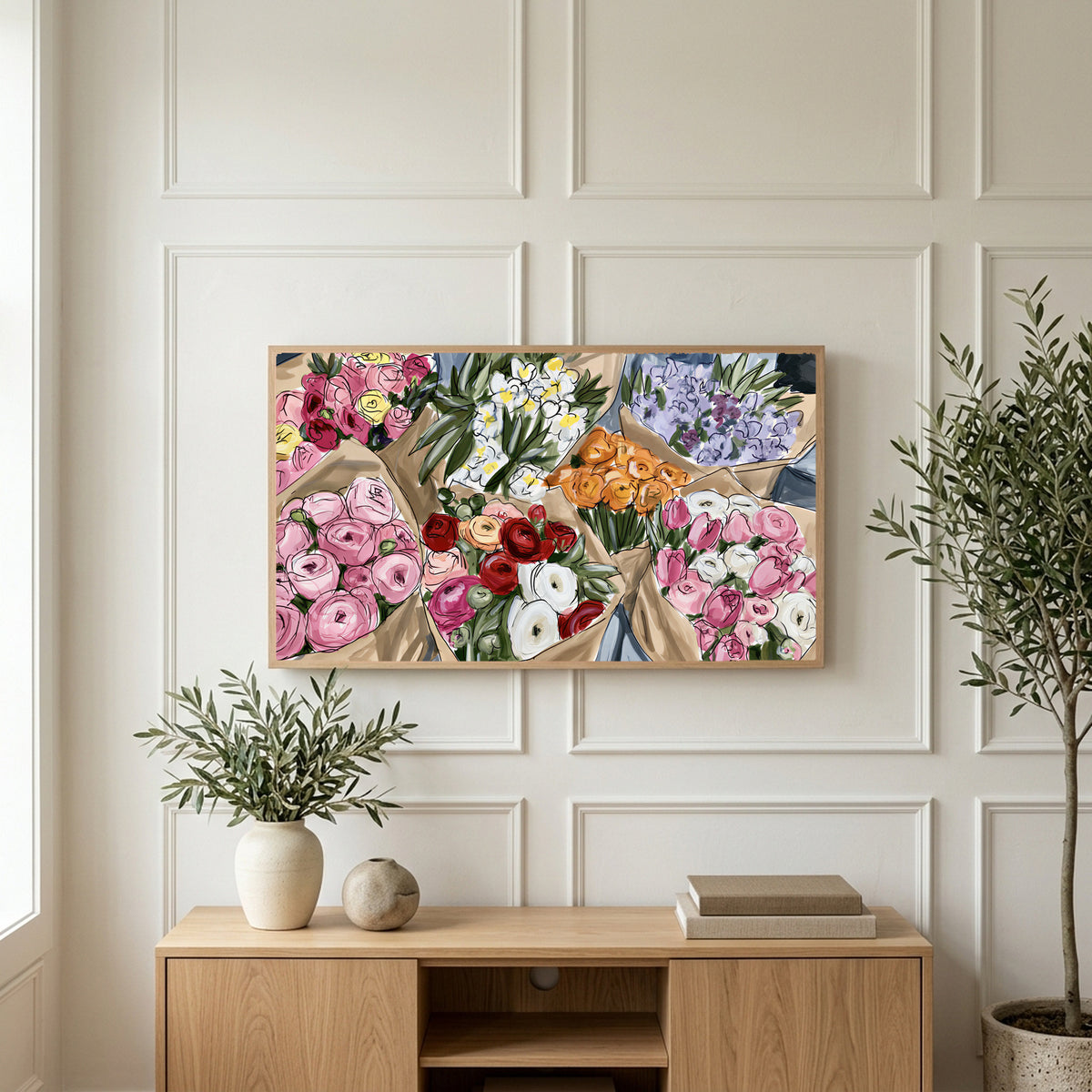 Flower bouquets art on a TV above a light oak sideboard with olive branches in a bright living room