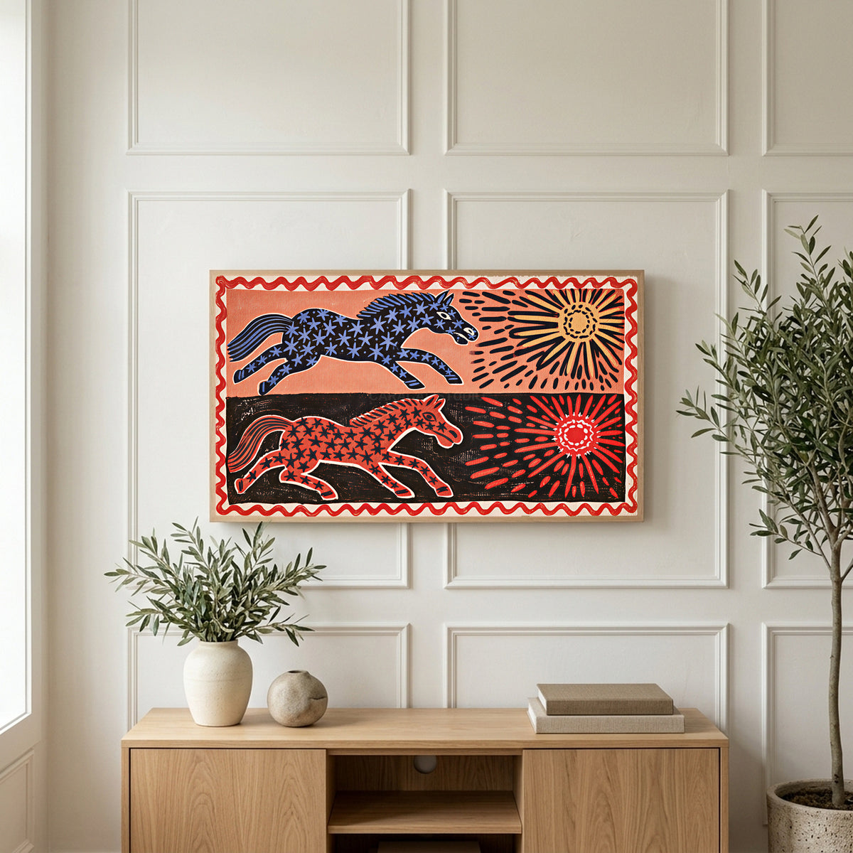 Folk star horses art on a TV above a light oak sideboard with olive branches in a bright living room