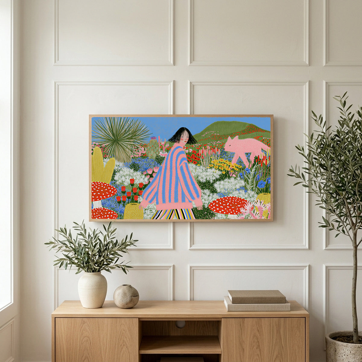 Flower garden and pink fox art on a TV above a light oak sideboard with olive branches in a bright living room