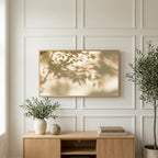 Leaf shadow art on a TV above a light oak sideboard with olive branches in a bright living room