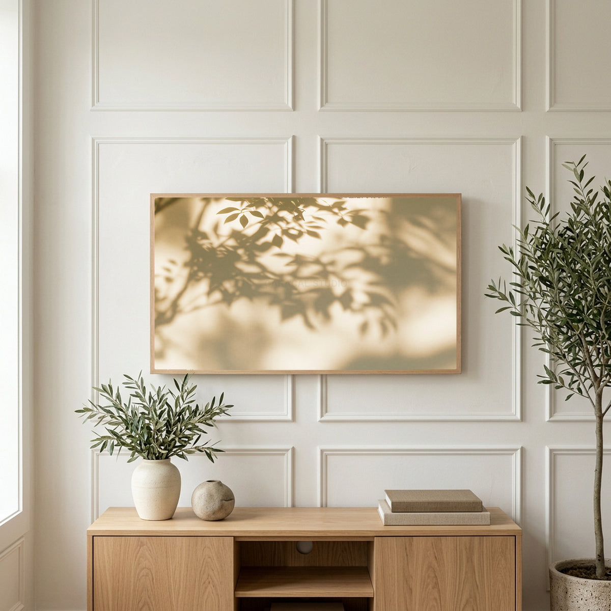 Leaf shadow art on a TV above a light oak sideboard with olive branches in a bright living room