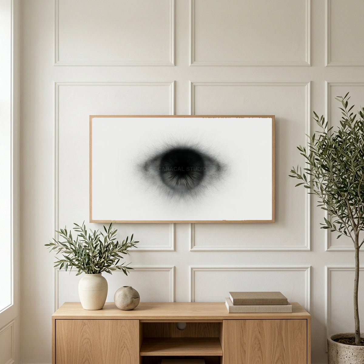 Black and white eye art on a TV above a light oak sideboard with olive branches in a bright living room