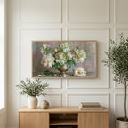 Peonies in a brass urn art on a TV above a light oak sideboard with olive branches in a bright living room