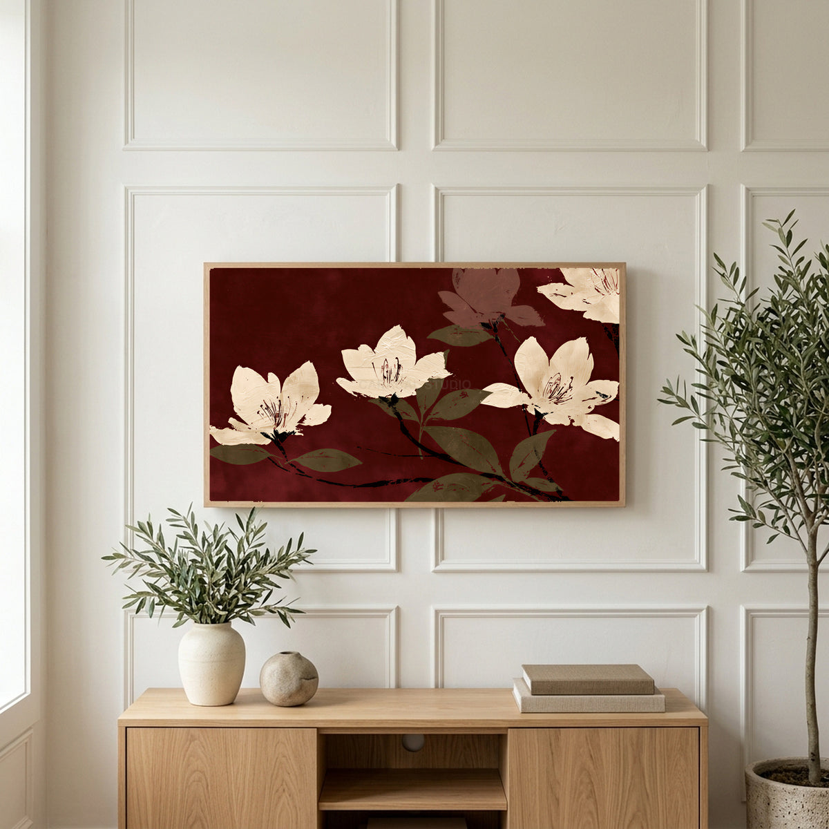 Cream blossoms on burgundy art on a TV above a light oak sideboard with olive branches in a bright living room