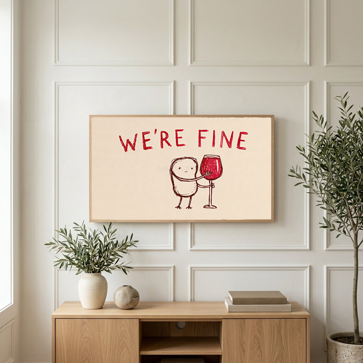 We're Fine wine doodle art on a TV above a light oak sideboard with olive branches in a bright living room