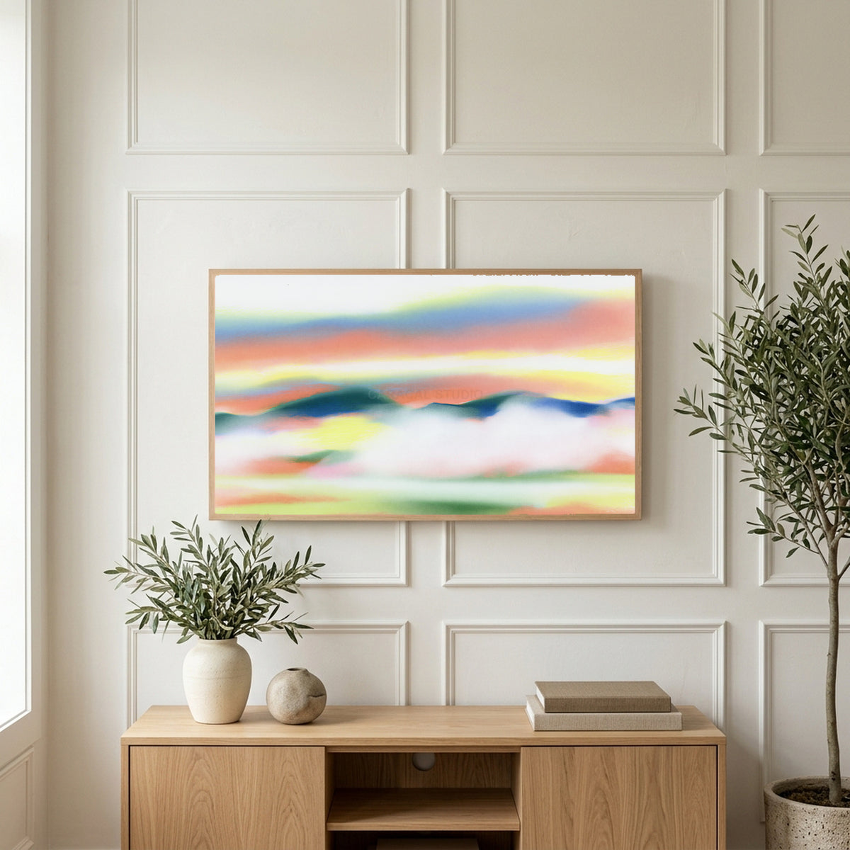 Abstract sunset hills art on a TV above a light oak sideboard with olive branches in a bright living room