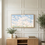 Cherry blossom tree art on a TV above a light oak sideboard with olive branches in a bright living room