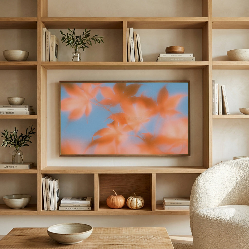 Autumn leaves art on a TV in built-in oak shelves with pumpkins and books