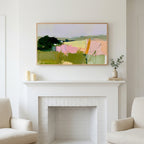 Abstract countryside art above a white fireplace with candles and eucalyptus on the mantel